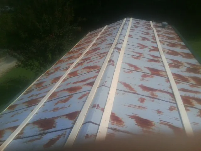 Rusted metal roof panels with new wood purlins before replacement — Storm Damage Roof Repair in Valley Grove by Roofing Brothers
