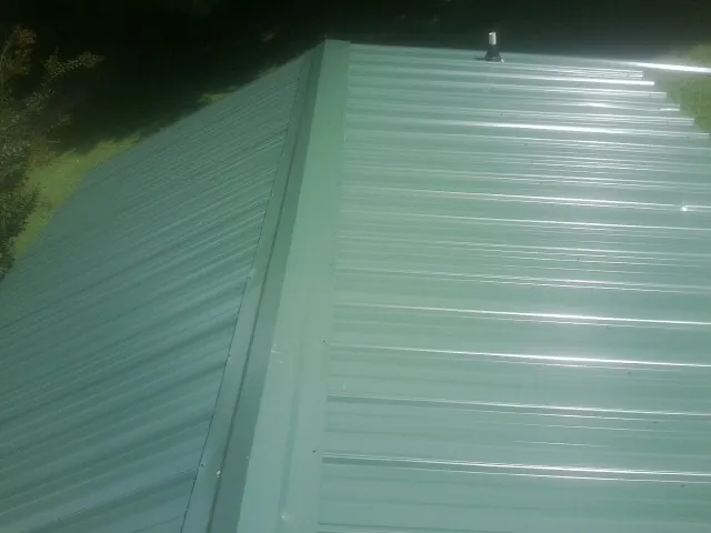 New green metal panels meeting at the ridge of a roof — Flat Roof Repair work by our crew in Valley Grove