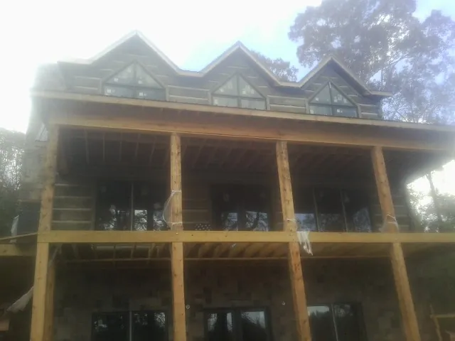 Dormers and porch framing on a large log home under construction — Roof Coating work by our crew in Valley Grove