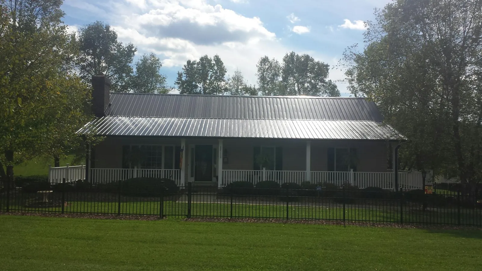 Gray metal roof on a brick ranch with a full width front porch in Valley Grove