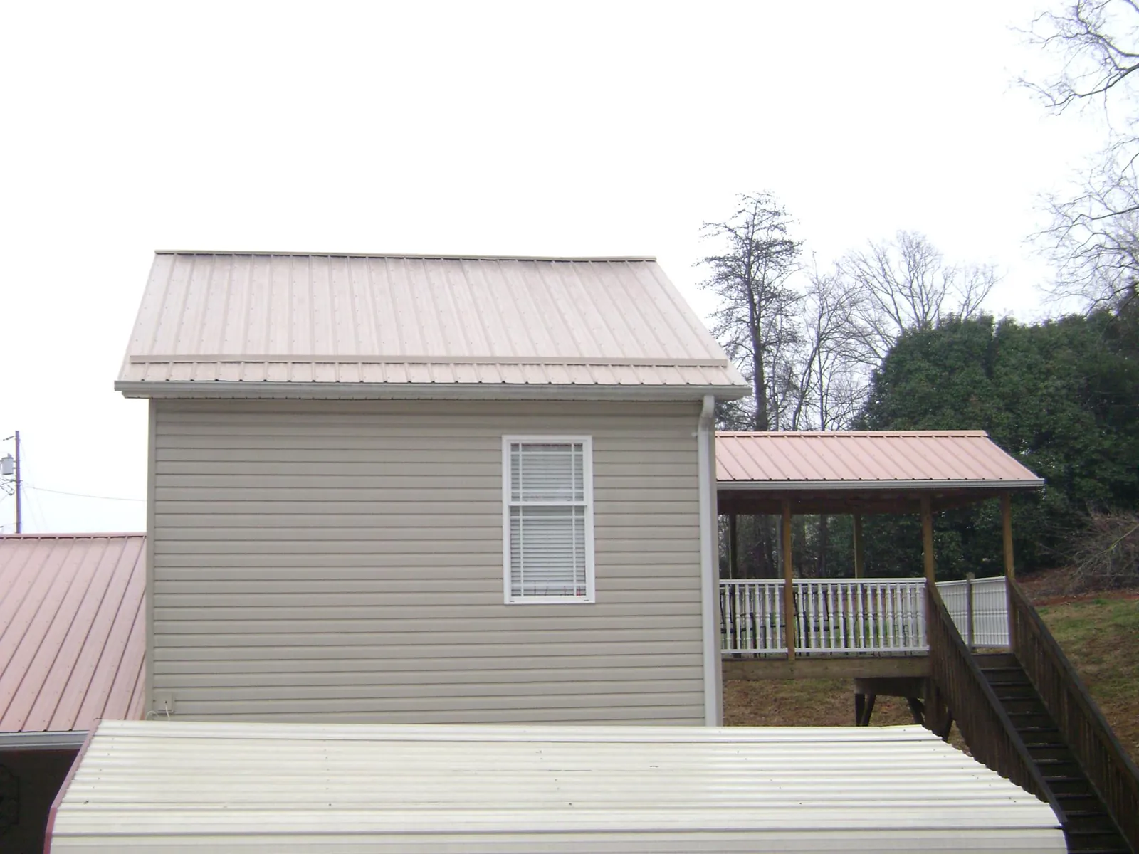 Tan metal roofs on a two story addition and attached porch, from a Roof Replacement job in Valley Grove