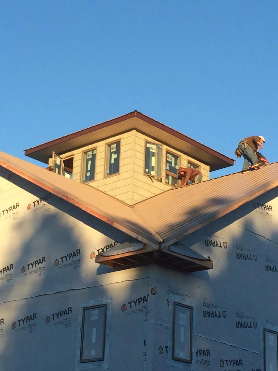 Roofers working around a rooftop cupola on a new metal roof at sunset — Roof Waterproofing in Valley Grove by Roofing Brothers